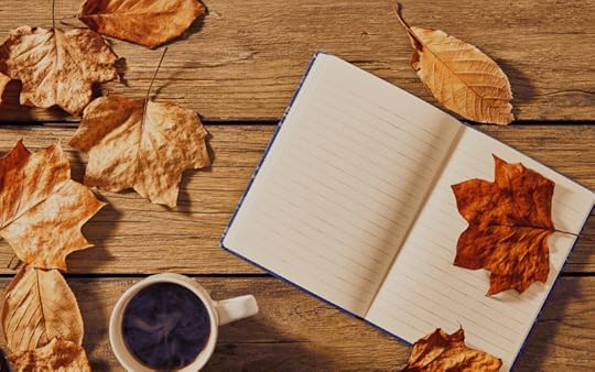 Notebook on a desk with coffee and leaves