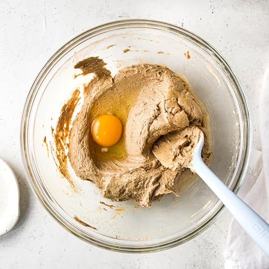 An overhead view of the lightened and fluffy chai cookie dough in a glass bowl, with one whole egg in the center, ready to be mixed in.