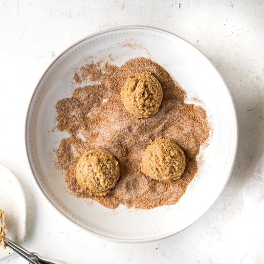 An overview of three round scoops of chai cookie dough resting in a generous pile of sugar-spiced cookie coating waiting to be covered in the mixture.