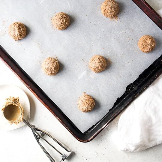 Seven round scoops of sugar spiced coated chai snickerdoodle cookie dough evenly on a parchment lined baking sheet, ready for baking.