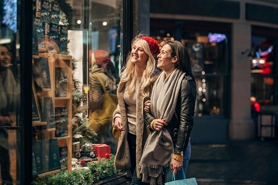 Dwie kobiety z zakupami oglądające świąteczne witryny sklepu