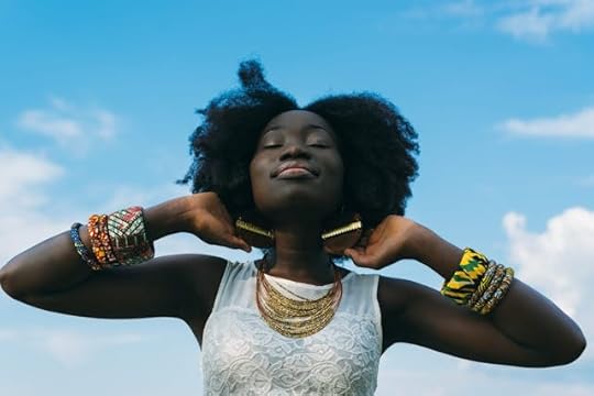 Woman smiling peacefully under a blue sky, symbolizing positivity and affirmations to have a good day