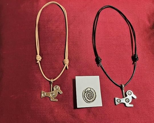 Three newly forged bits of Early Medieval style jewellery against a red background: two ducks flanking a snakestone