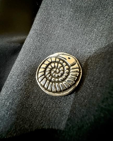 Silver snakestone pin on the lapel of a grey suit jacket