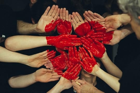 A circular arrangement of hands with red paint forming heart shapes, symbolizing connection and emotion.