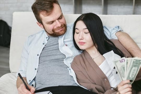 Couple sitting together with money and a notebook, symbolizing how thoughts create reality and financial abundance
