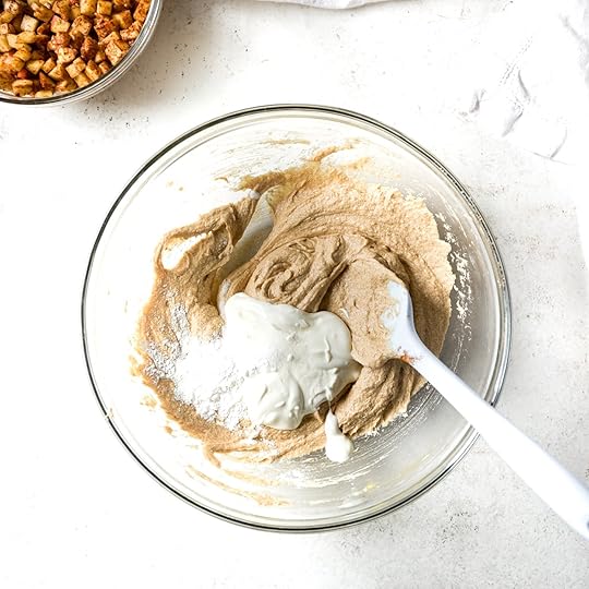 Overhead view showing the addition of sour cream, baking powder, baking soda, salt into the creamed muffin batter base for apple cinnamon muffins.