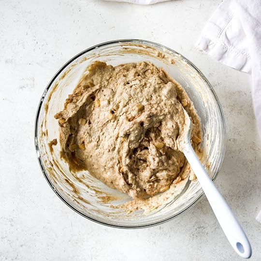 Apple Cinnamon Muffin batter all ready to be baked in a glass mixing bowl on a white surface.