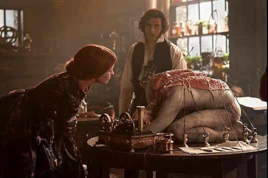 Elizabeth (Mia Goth) and Victor (Oscar Isaac) bond over a dissected body in the lab. Elizabeth is leaning in, looking at the exposed spine of the trussed up, kneeling figure on the table, and Victor hangs back, looking anxious. 