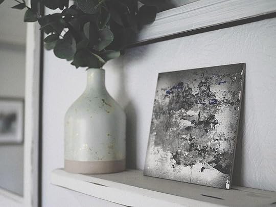 a vase with a plant on a shelf next to a picture