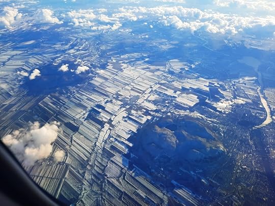 Aerial view of small farms, interrupted by two small rocky mountains.