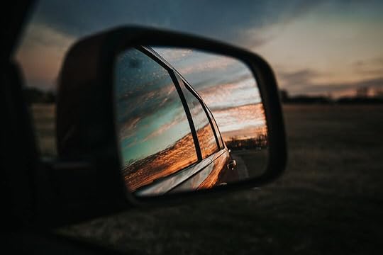 black car side mirror reflecting orange and white cloudy sky during daytime