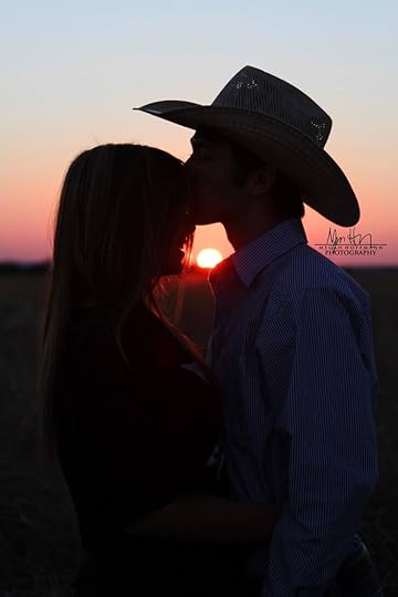 This may contain: a man and woman kissing in front of the sun at sunset on a farm field