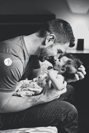 This may contain: a man sitting on a bed holding a baby