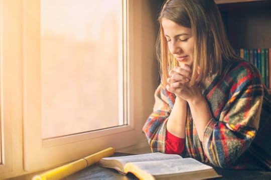 Woman praying with clasped hands over an open Bible by a sunlit window — what does affirmation mean in the Bible.