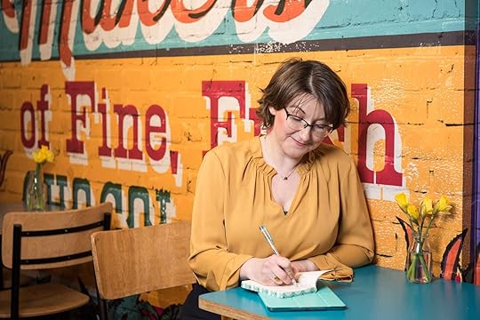 Elizabeth Harrin wearing a yellow top in a cafe, writing in a notebook