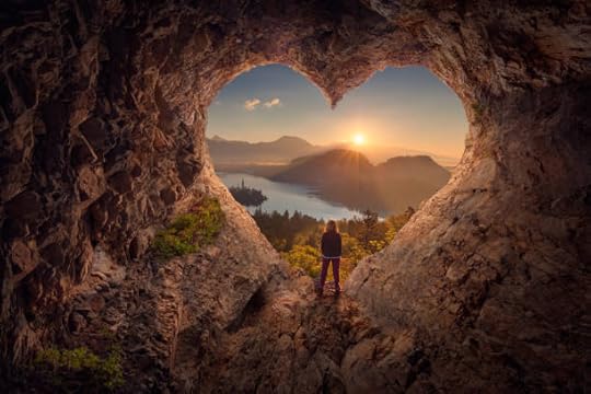 Person viewing sunrise through a heart-shaped cave, reflecting on purpose and direction.