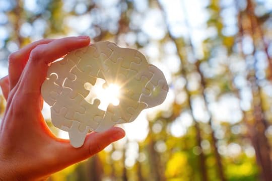 Hand holding a brain-shaped puzzle in bright sunlight — manifest dream life while you sleep clarity.