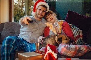 Young couple and their dog watch a movie at Christmastime
