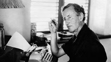 Ian Fleming sitting at his typewriter.