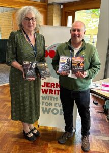 photo of Debbie and Rory holding Rory's books in front of a Jericho Writers banner