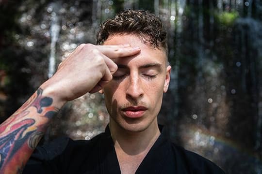 Person touching the center of their forehead with eyes closed in a calm setting, symbolizing awareness of third eye chakra opening symptoms.