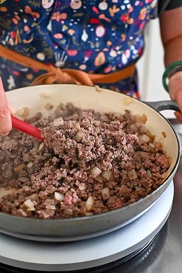 A closeup of ground beef and onions in a large gray skillet cooked until the beef is no longer pink.