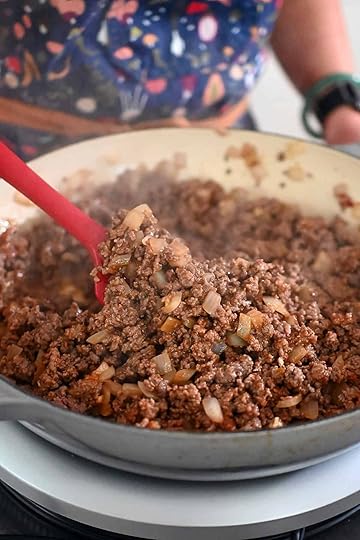 A closeup of the seasoned ground beef and onions before the vegetables and sauce are added to the skillet.