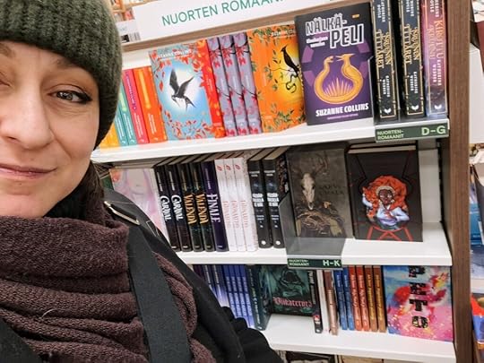 Kirjailija Hai talvitamineissaan Akateemisen kirjakaupun nuortenkirjahyllyllä, jossa vierekkäin Sarvijumala ja Kuunkehä.