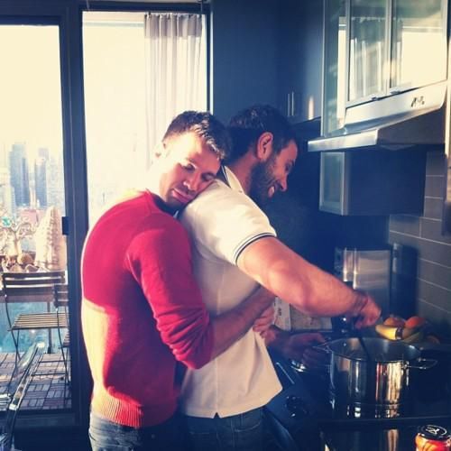 This may contain: two men in the kitchen cooking together with one holding his arm around the other's shoulder