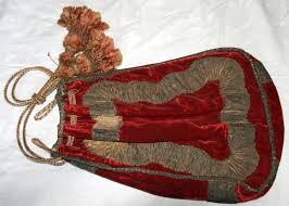 A vintage red velvet drawstring pouch with decorative gold trim and tassels.