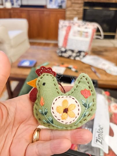 Marie's hand holding up a felted chicken