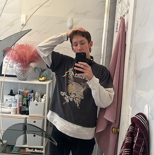 David is taking a mirror selfie. They're wearing a Metallica t-shirt over a white long-sleeve shirt and black jeans.