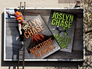 Man on ladder pasting up a billboard ad of the first two Riley Forte thriller books by Joslyn Chase--Nocturne in Ashes and Staccato Passage