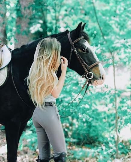 This may contain: a woman standing next to a black horse in the middle of a forest with trees