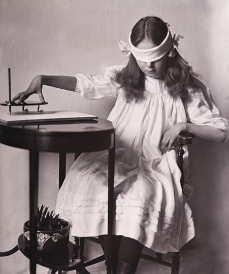 black and white vintage photo of a a young girl operating a planchette