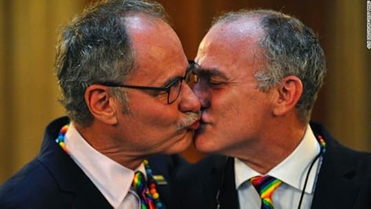 This may contain: two men in suits kissing each other with their noses close to one another, both wearing colorful ties
