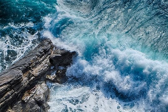 Fast blue waves crashing on gray rocks