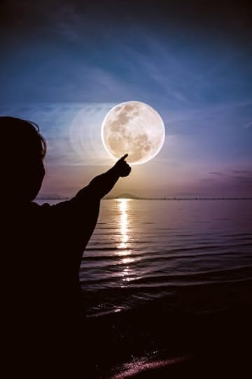 Silhouette of a child pointing towards a large moon over a calm sea at twilight.