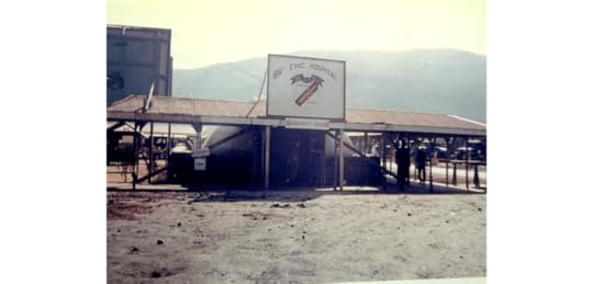 An old photograph of a military hospital building with a sign that reads '35th Evac Hospital'. The structure is supported by posts and is located in a dusty area with mountains in the background.