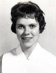 Black and white portrait of a young woman with short, curly hair, smiling and wearing a white collar.