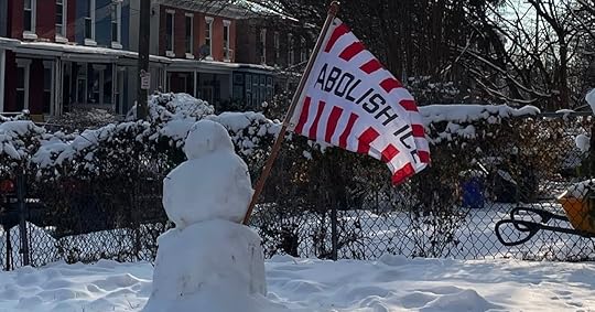Snowman in a snow-covered yard holds a red and white striped flag with 