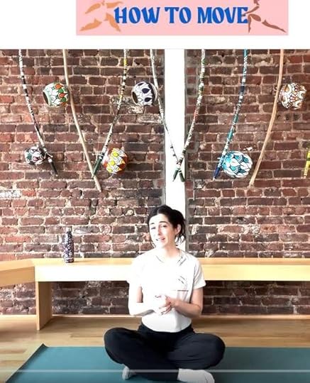 Anna Maltby seated on a mat on the floor looking to the viewer, behind her a bench and exposed brick wall.