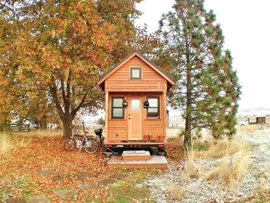 This may contain: a small wooden cabin sitting in the middle of a field with trees and bicycles parked next to it