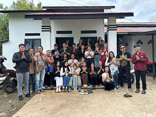 Foto grup Mahéng (Rahmat Ali) bersama Karmele Llano Sánchez dan tim besar Yayasan IAR Indonesia di depan sebuah rumah beratap merah di Ketapang, Kalimatan Barat. Mahéng tampak mengenakan kaos abu-abu, jongkok di barisan belakang seorang anak kecil, tepat di belakang Karmele Llano Sánchez yang duduk di tengah depan. Visual kebersamaan ini mengilustrasikan esai reflektif Mahéng berjudul 'Mengapa Maaf Lahir Batin Bisa Jadi Kalimat yang Paling Susah Kita Ucapkan untuk Diri Sendiri?'. Sebagai penulis buku Runduma: Surga Kecil di Wakatobi dan novel Nayanika serta lulusan Sosiologi Agama UIN Sunan Kalijaga Yogyakarta, Mahéng konsisten membedah hubungan antara narasi sosial, tanggung jawab moral, dan pengalaman kemanusiaan di Ketapang.