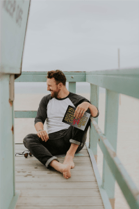 Man on deck of beach house holds Cincher's Waltz by Joslyn Chase