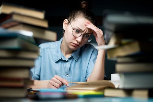 The student looks tiredly at the study materials, but continues to study late at the table, preparing for exams
