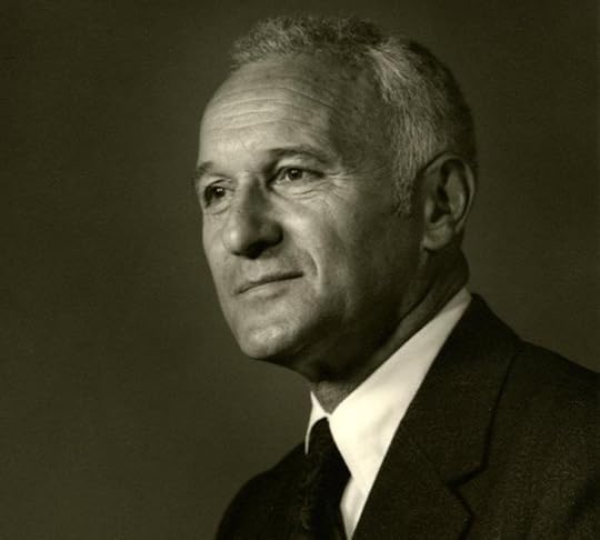 Black and white portrait of a man in a suit, with short gray hair, looking to the side with a thoughtful expression.