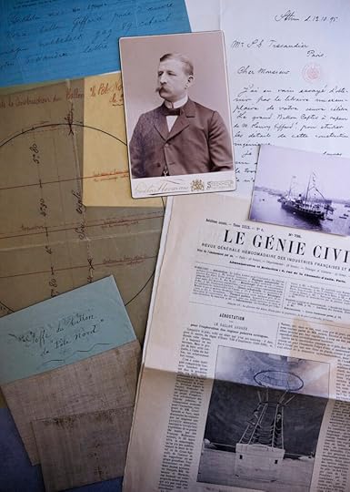 A color photograph of several items -- newspaper articles, a sepia-toned photo, maps and charts, displayed on a table.