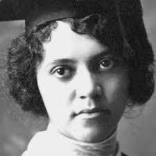 Black and white portrait of a young woman wearing a graduation cap and looking directly at the camera.